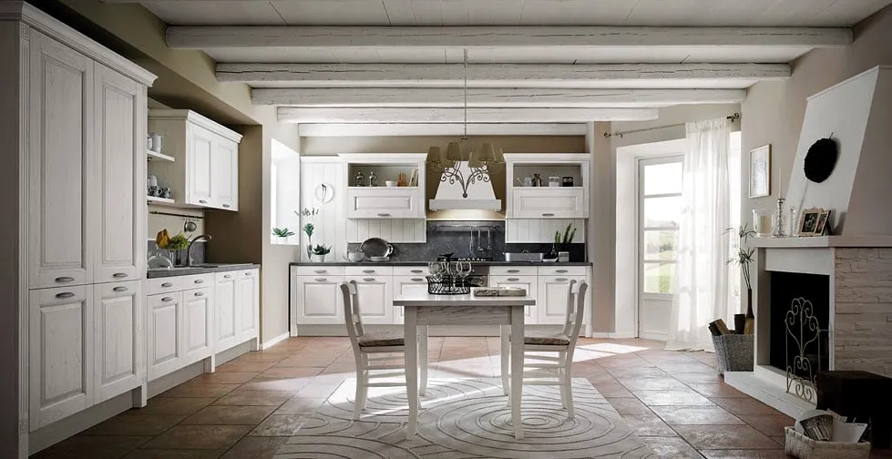 Cucina classica avorio accanto al camino, con travi di legno al soffitto